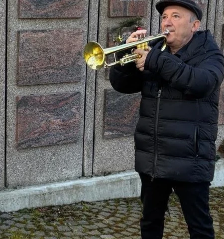 Johann Schan spielt Trompete an einer Urnenwand